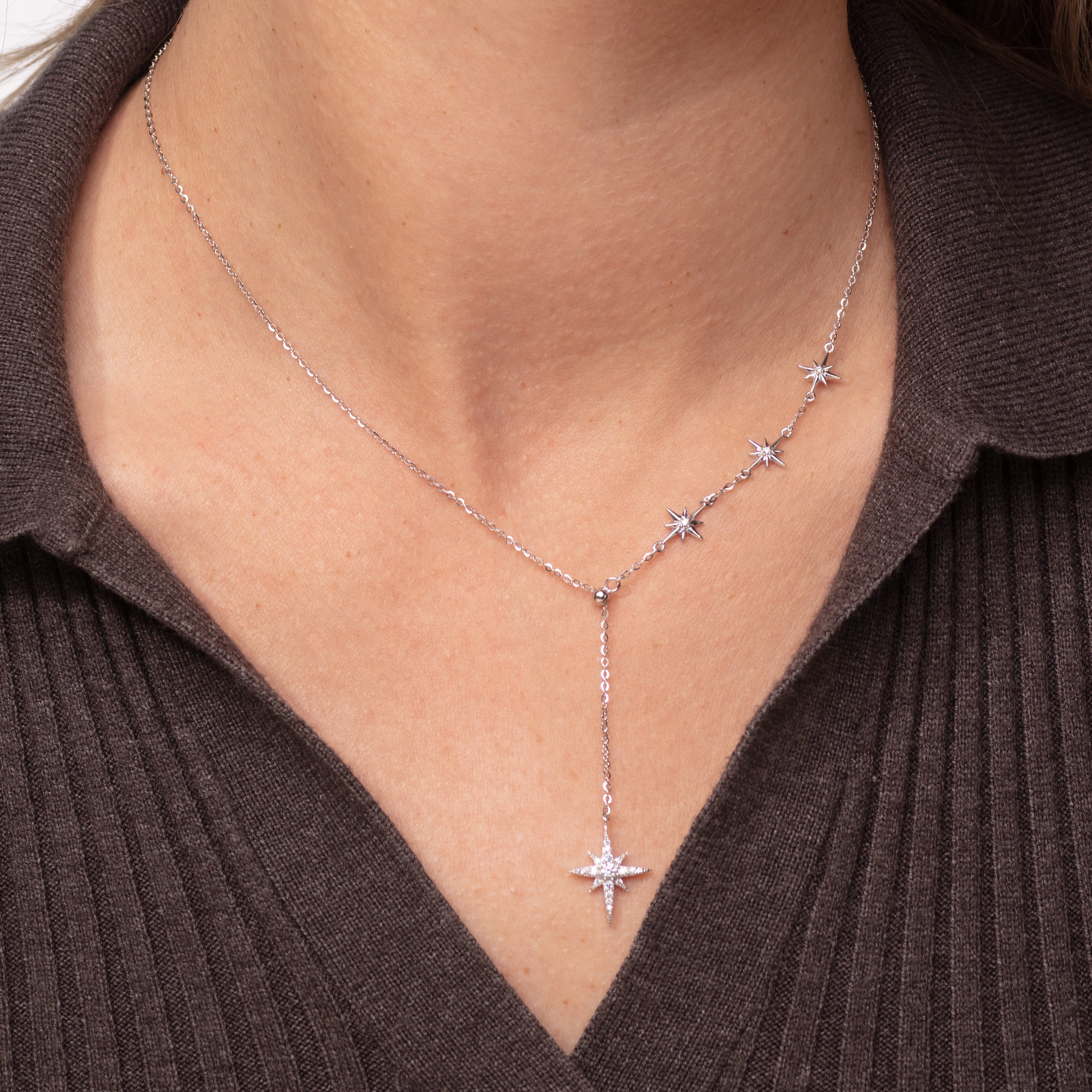 Star-shaped necklace worn by a person against a brown background