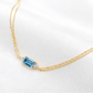 Gold necklace with a blue gemstone on a white background