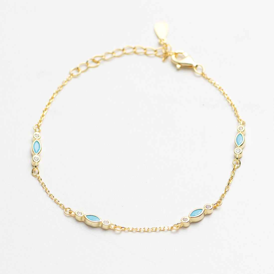 Gold bracelet with blue gemstones on a white background