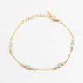 Gold bracelet with blue gemstones on a white background