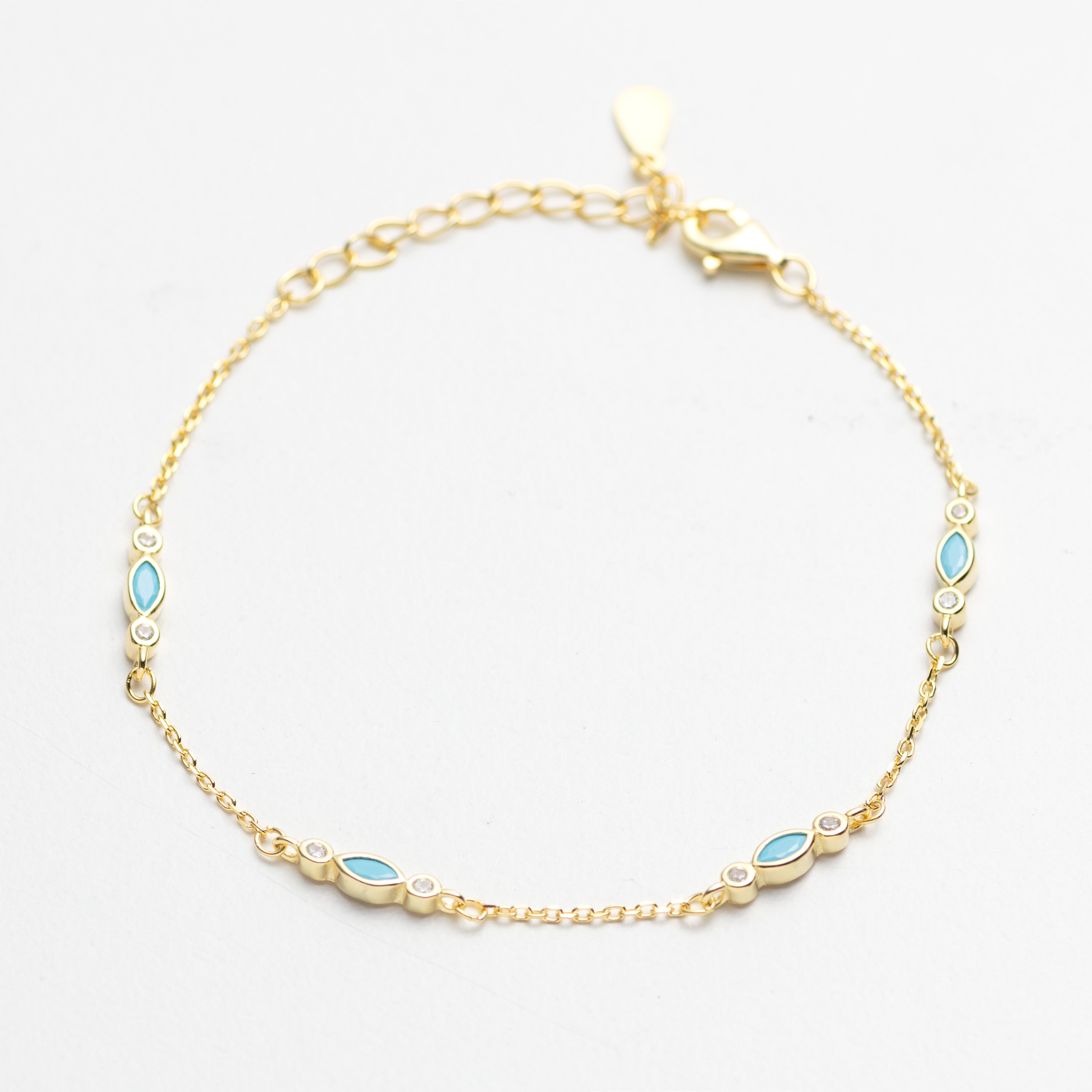 Gold bracelet with blue gemstones on a white background