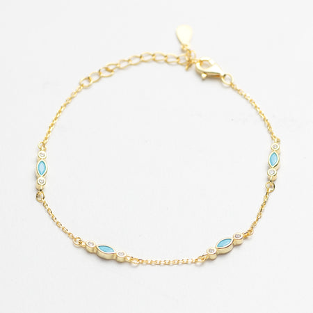 Gold bracelet with blue gemstones on a white background