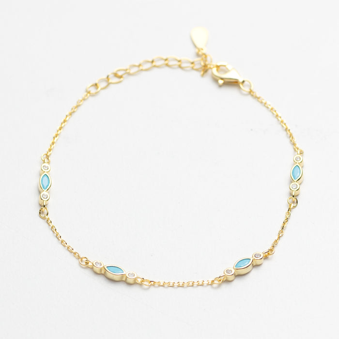 Gold bracelet with blue gemstones on a white background