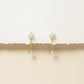Gold earrings with gemstones on a beige background