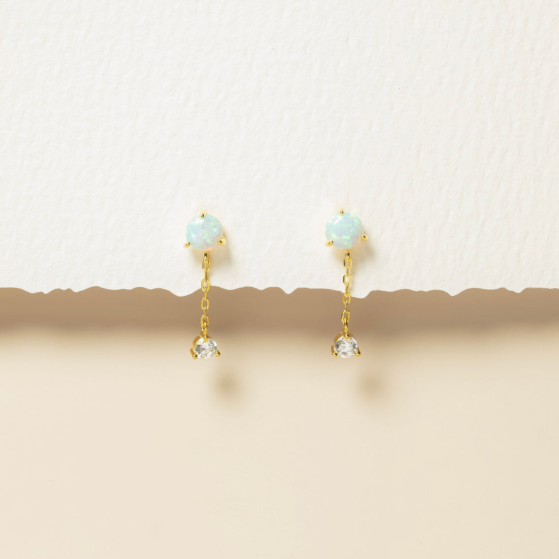 Gold earrings with gemstones on a beige background