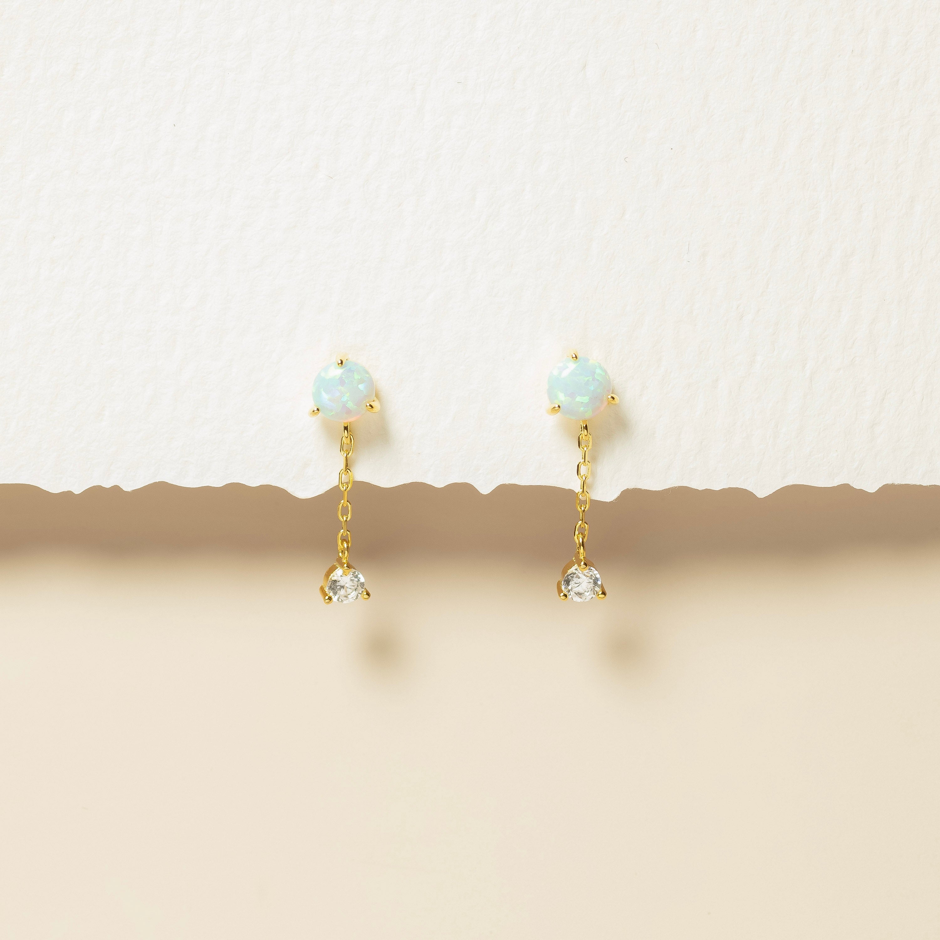 Gold earrings with gemstones on a beige background