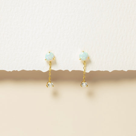 Gold earrings with gemstones on a beige background