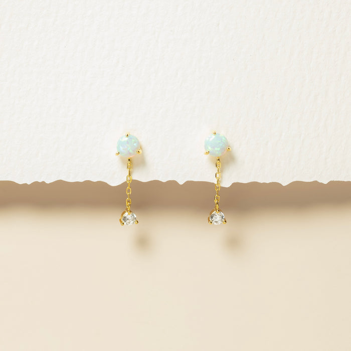 Gold earrings with gemstones on a beige background