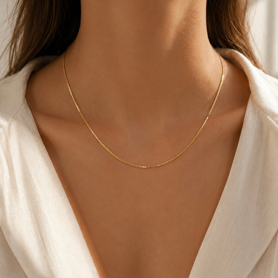 Gold necklace on a person wearing a white shirt