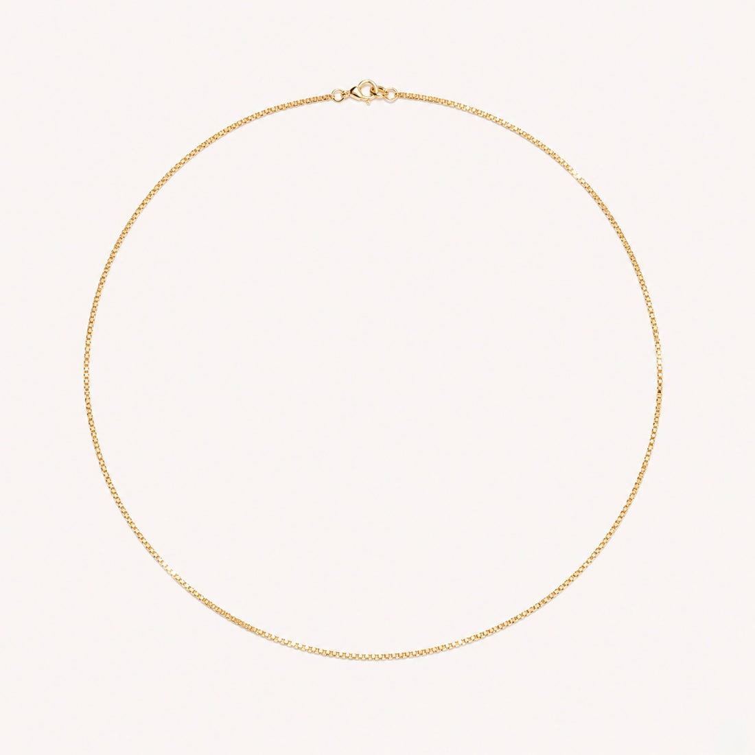 Gold necklace on a light pink background