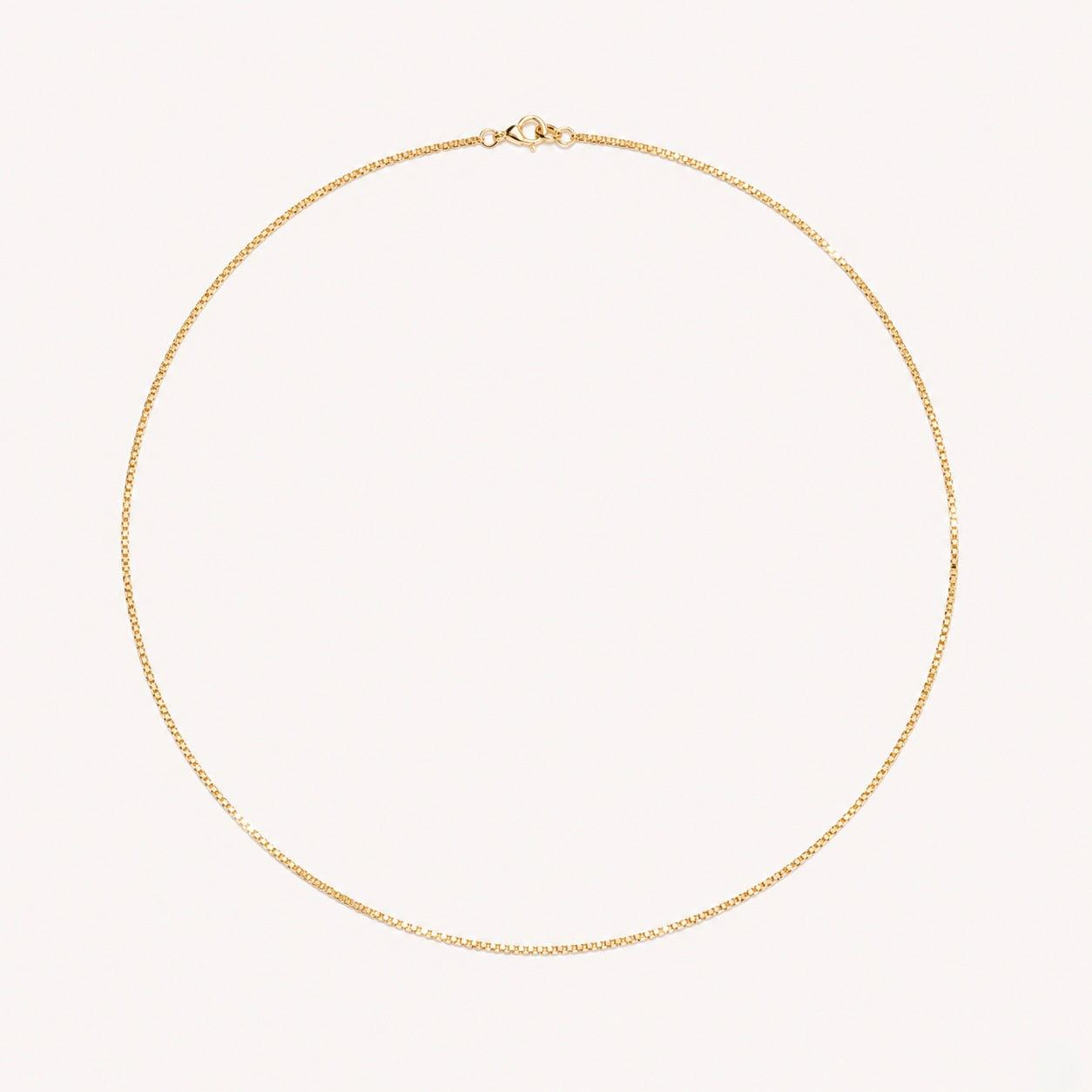 Gold necklace on a light pink background