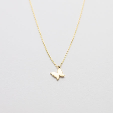 Gold butterfly necklace on a light gray background