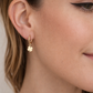 Close-up of a woman wearing a gold earring with a clover design.