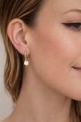 Close-up of a woman wearing a gold earring with a clover design.
