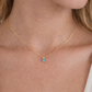 Gold necklace with a blue pendant on a person's neck