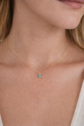 Gold necklace with a blue pendant on a person's neck
