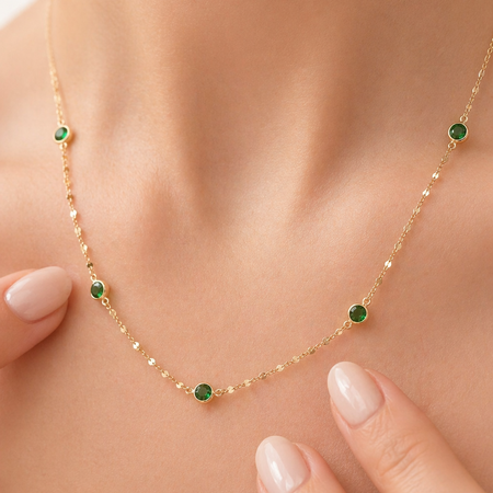 Gold necklace with green gemstones worn by a person