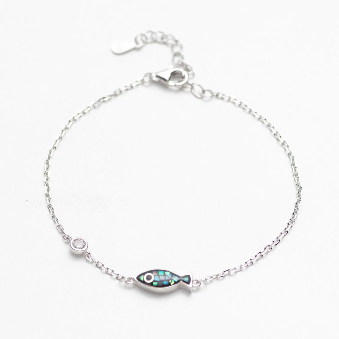 Silver bracelet with a fish-shaped charm on a white background
