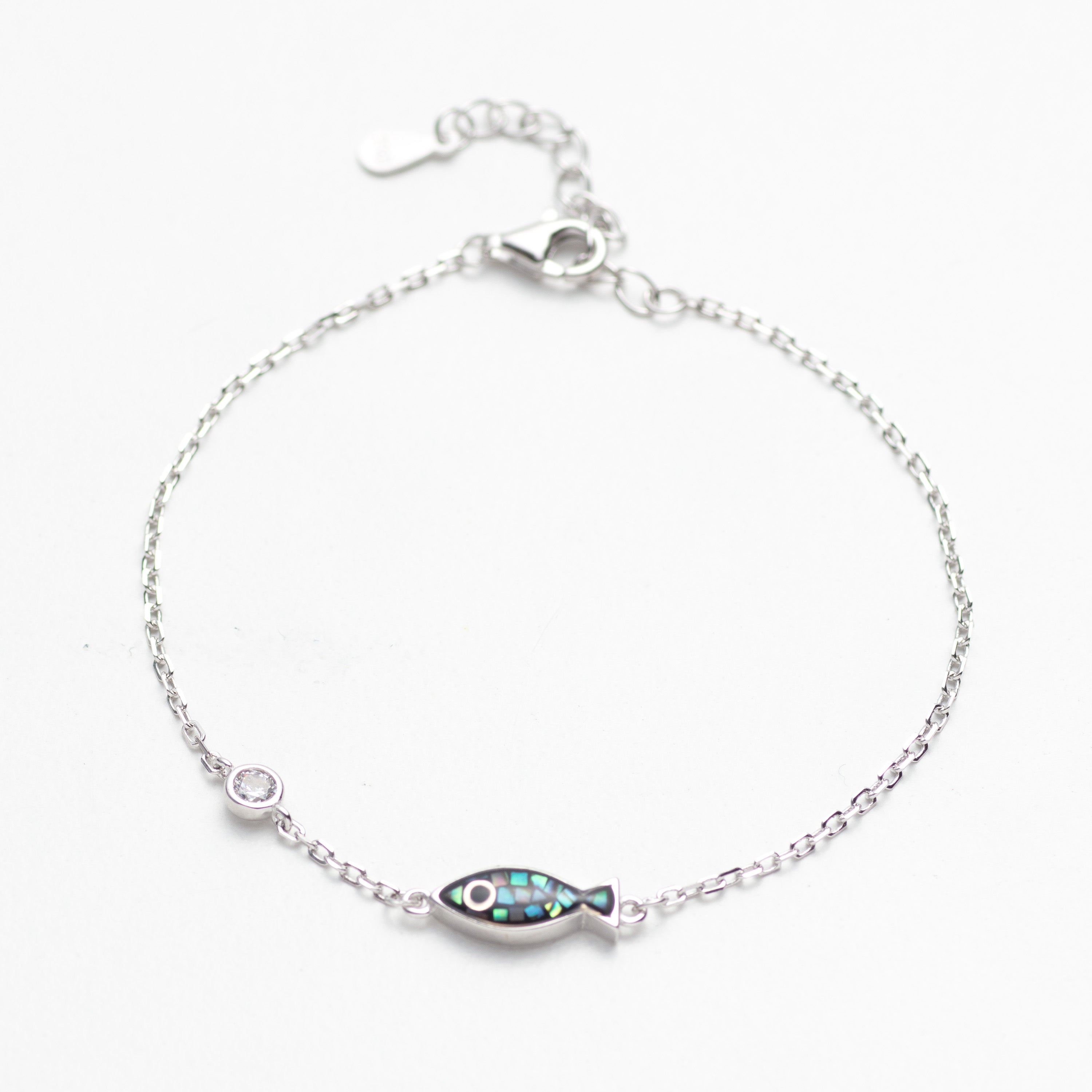 Silver bracelet with a fish-shaped charm on a white background