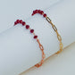 Bracelet with red beads and gold chain on a light background