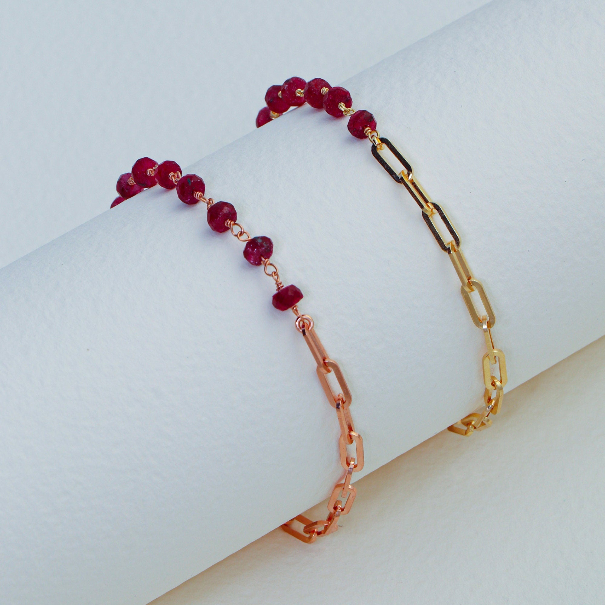 Bracelet with red beads and gold chain on a light background