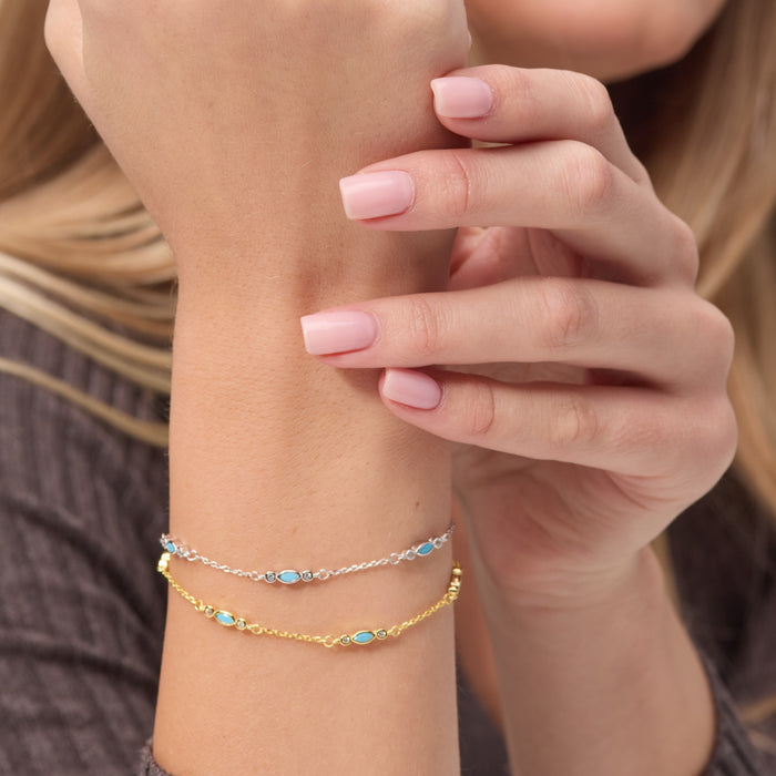 Close-up of a person's wrist wearing two gold bracelets with blue stones.