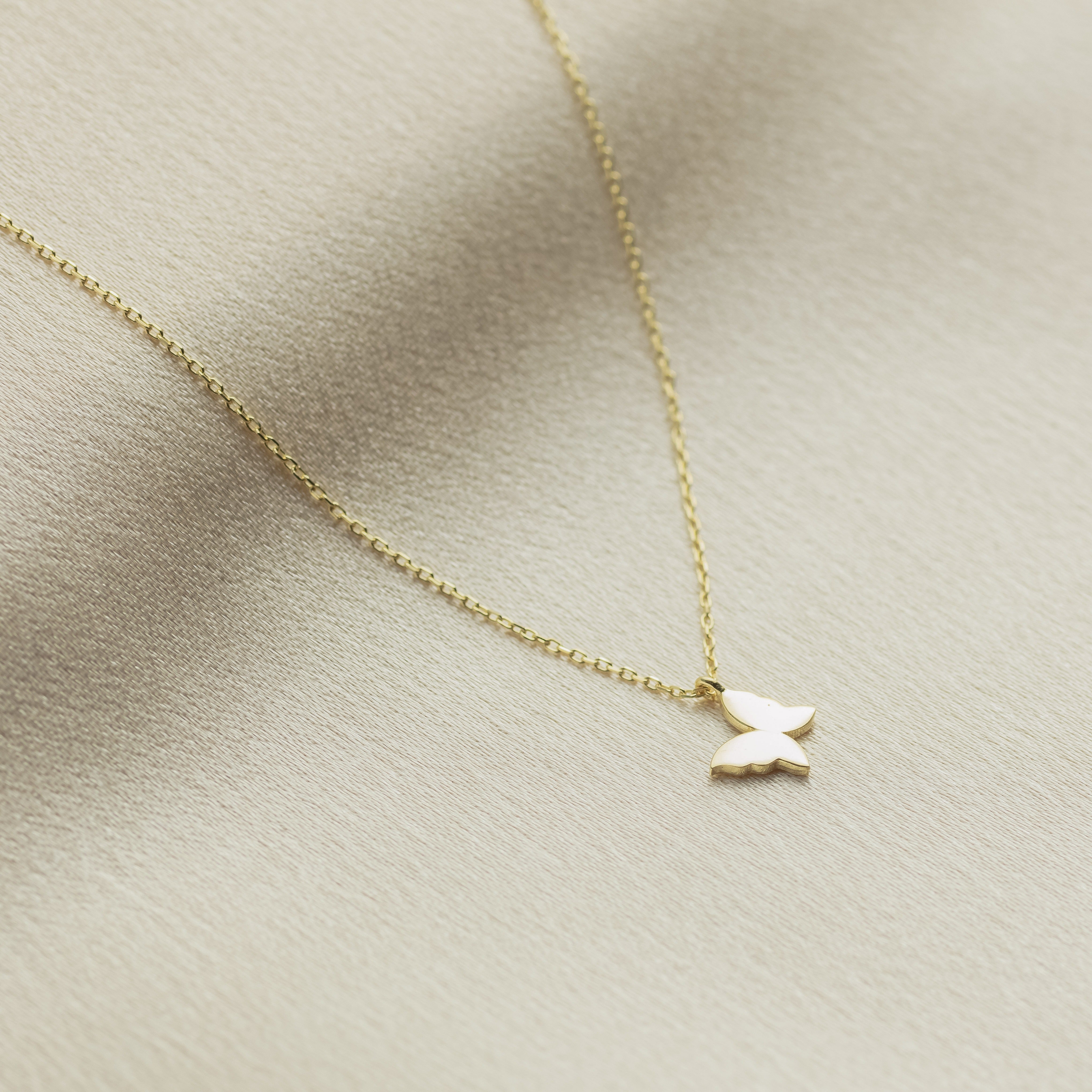 Gold necklace with a small pendant on a beige fabric background