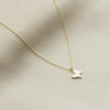 Gold necklace with a small pendant on a beige fabric background