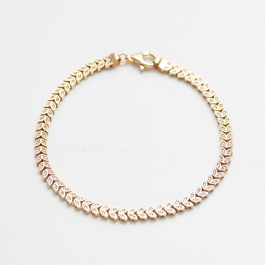 Gold bracelet with clear stones on a white background