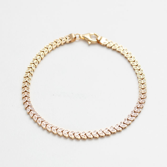 Gold bracelet with clear stones on a white background