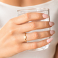 Hand wearing a gold ring with a clear glass of water