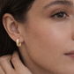 Close-up of a woman wearing a gold hoop earring.