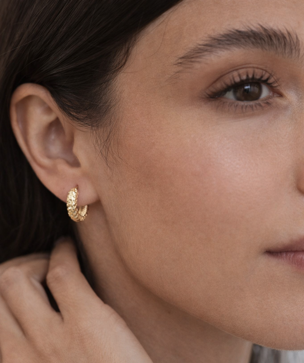 Close-up of a woman wearing a gold hoop earring.