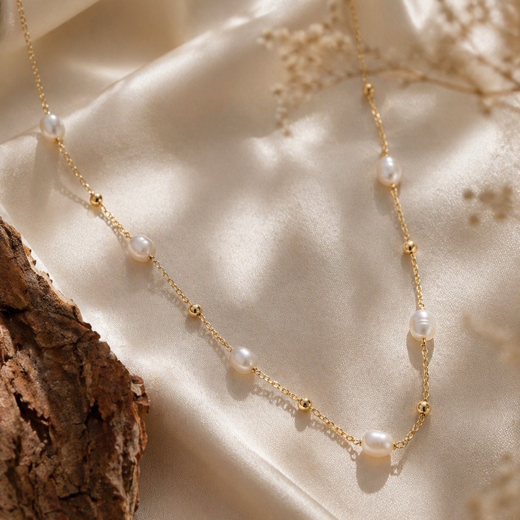 Gold necklace with pearls on a textured beige surface