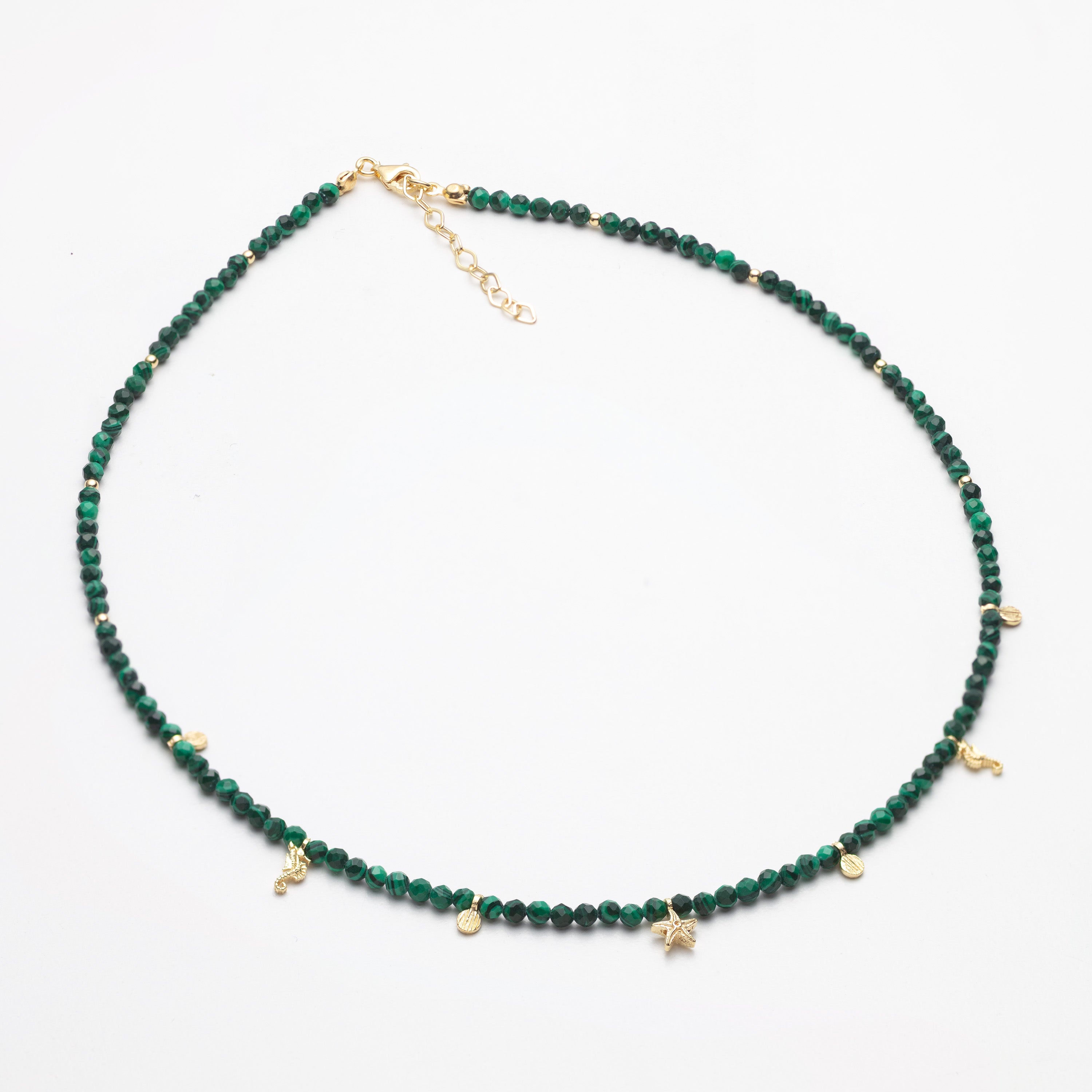 Green beaded necklace with gold accents on a white background
