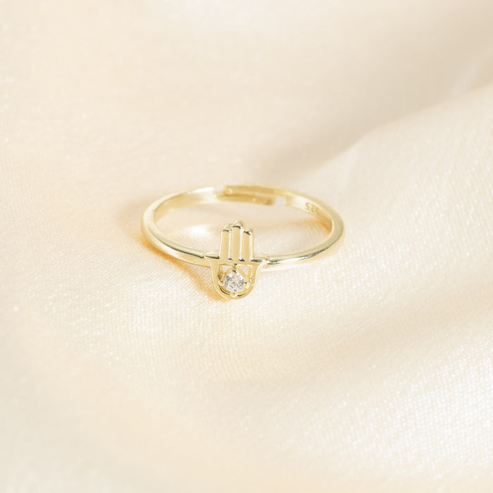 Gold ring with a diamond on a beige background