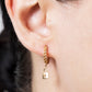 Gold hoop earring with a lock charm worn by a person.