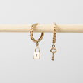 Gold chain bracelet with lock and key charms on a light gray background