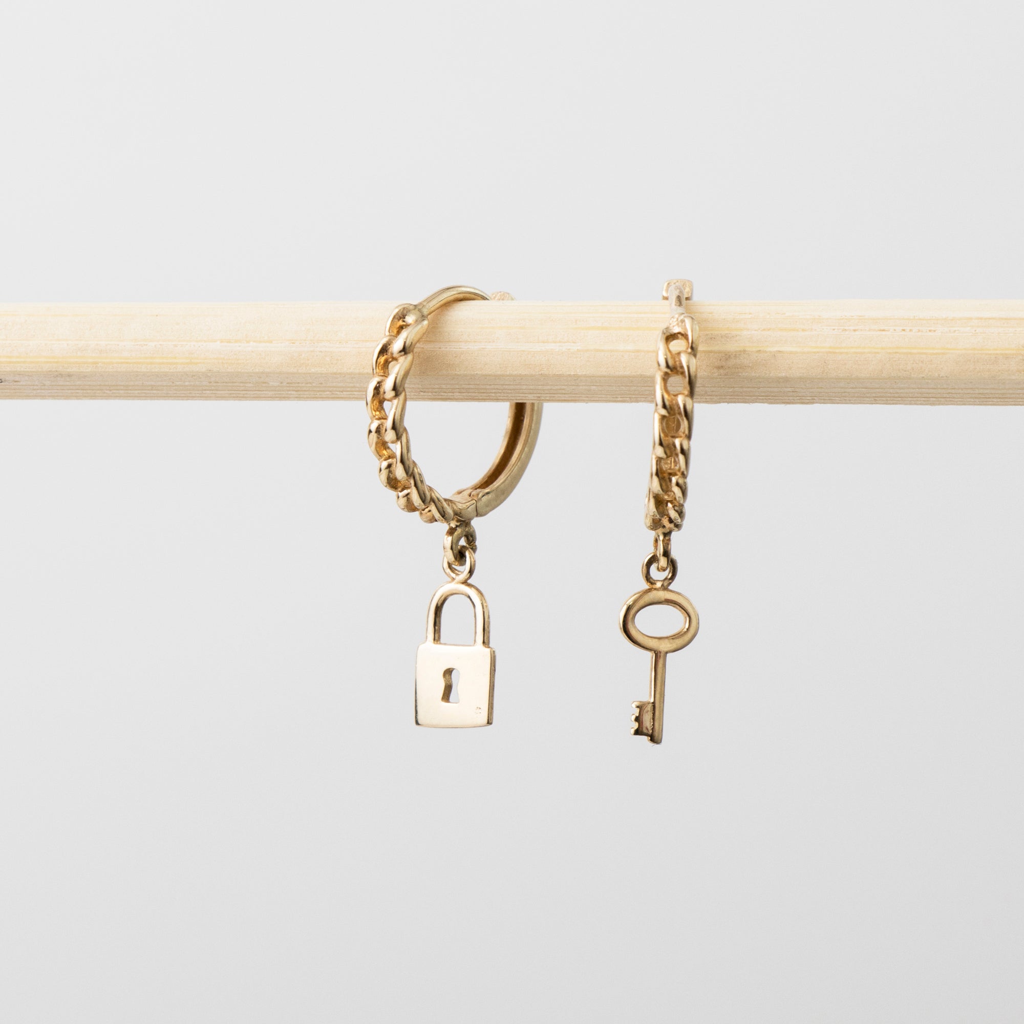 Gold chain bracelet with lock and key charms on a light gray background