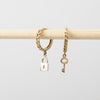Gold chain bracelet with lock and key charms on a light gray background