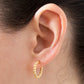 Gold hoop earring worn on an ear with a neutral background