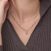 Gold necklace with a star pendant worn by a person in a brown ribbed sweater.