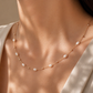 Pearl necklace on a person wearing a white garment with a neutral background