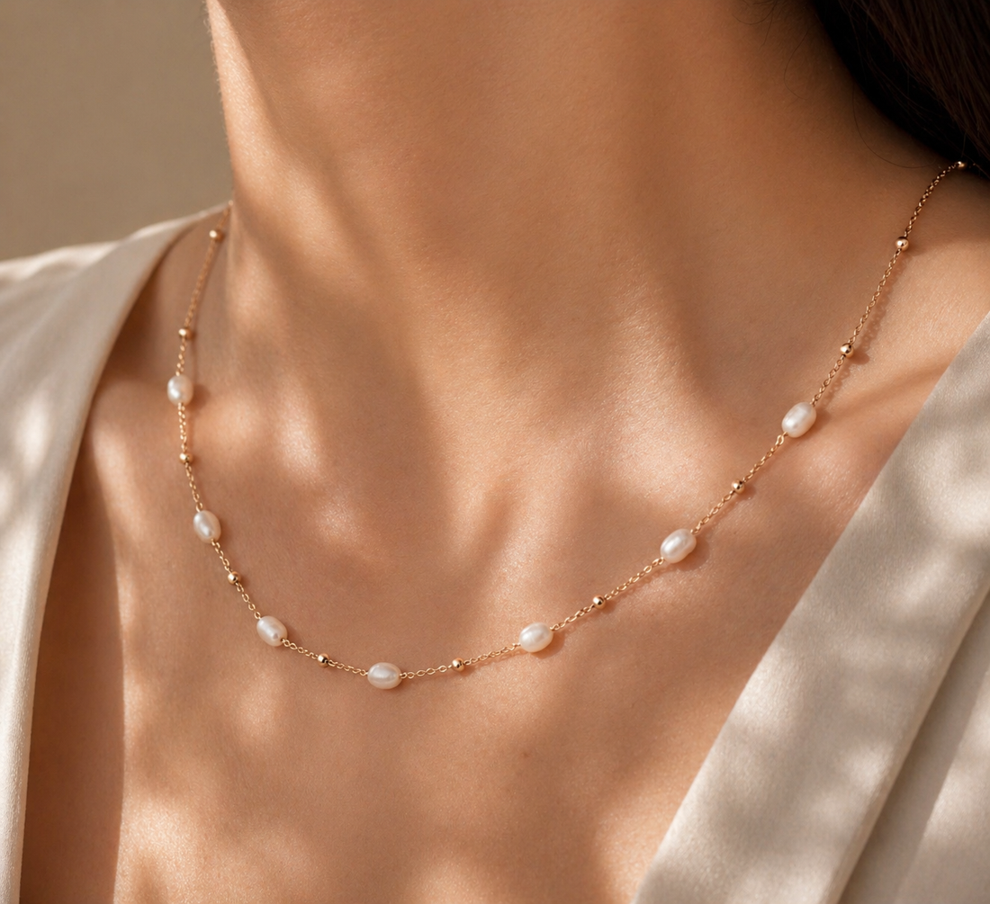 Pearl necklace on a person wearing a white garment with a neutral background