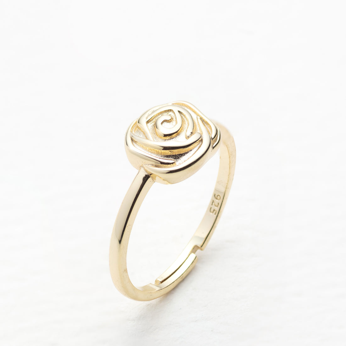Gold rose-shaped ring on a white background