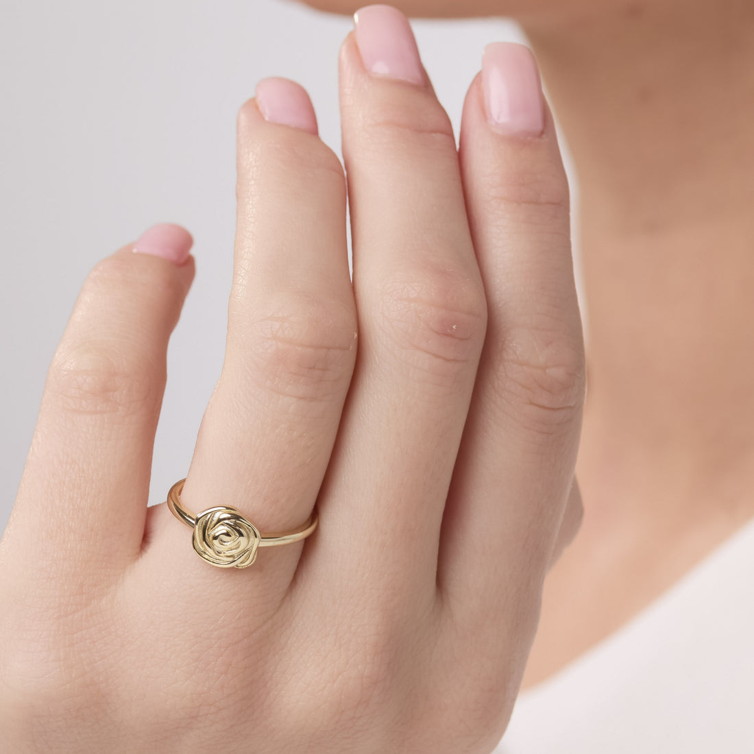 Gold ring on a finger with a plain background