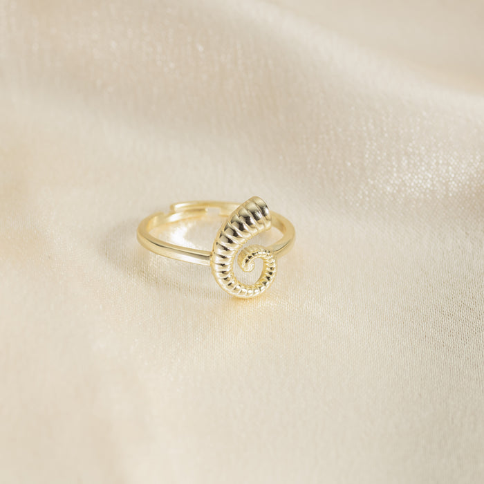 Gold spiral ring on a beige fabric background