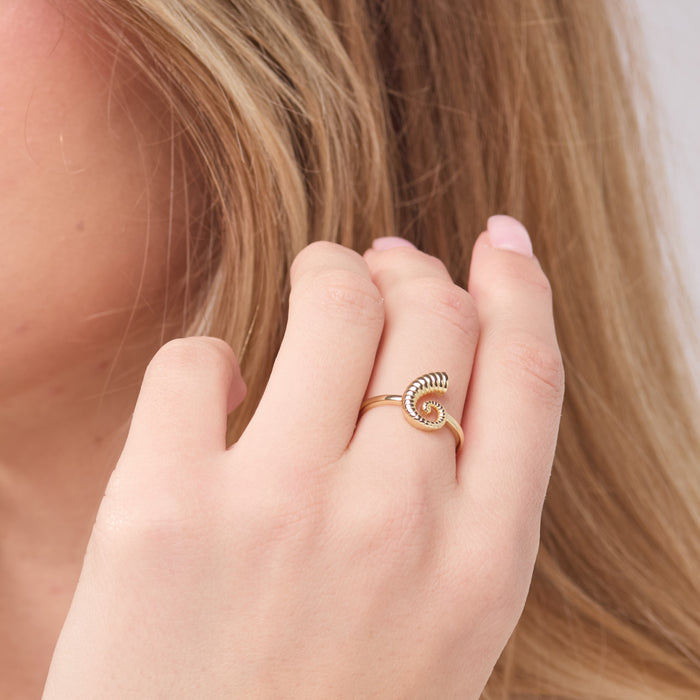 Hand wearing a gold ring with a blurred background