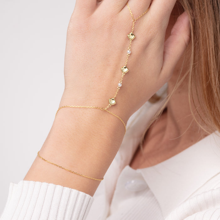 Gold anklets on a person's ankle against a light background