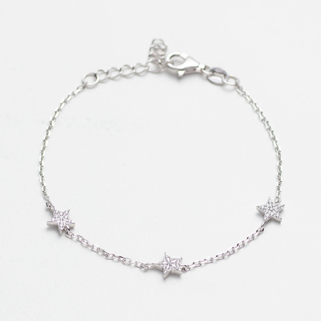 Silver bracelet with star-shaped charms on a light gray background